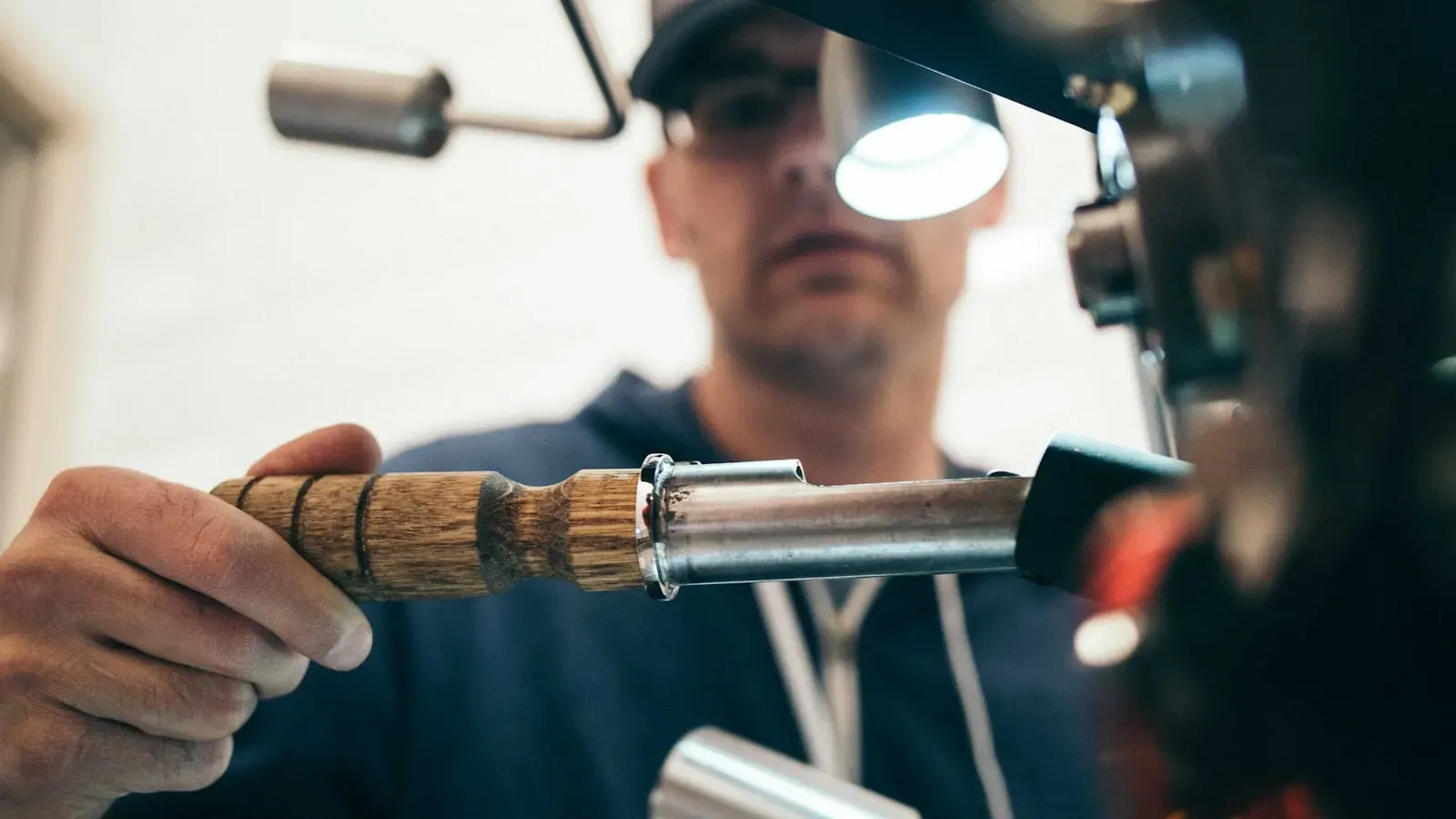 A machinist working a metal part at a machine in a workshop